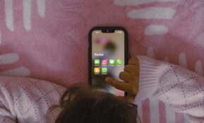 a person laying in bed holding a cell phone