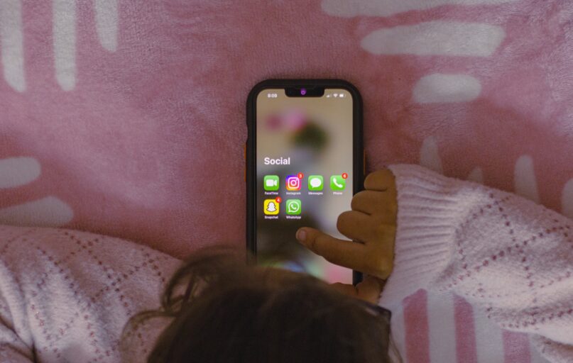 a person laying in bed holding a cell phone