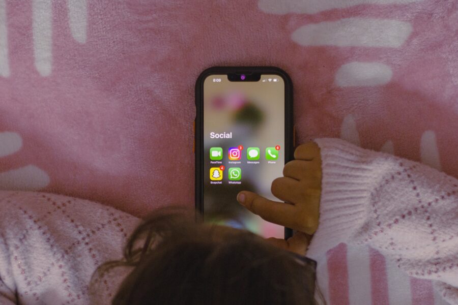 a person laying in bed holding a cell phone