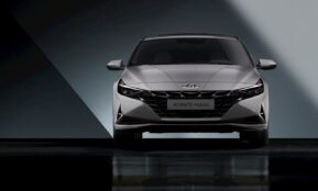 the front end of a silver car in a dark room