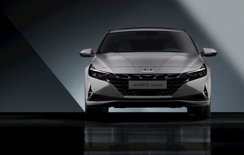 the front end of a silver car in a dark room