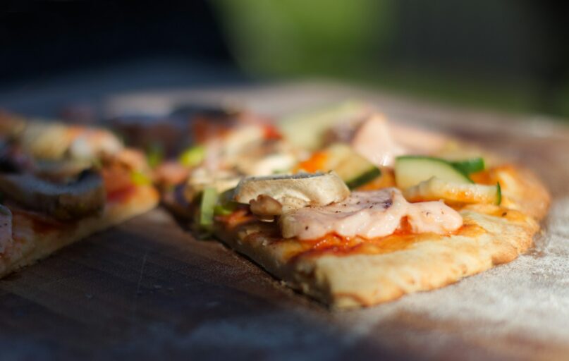 pizza with green vegetable on brown wooden table