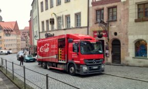 a red truck driving down a street next to tall buildings