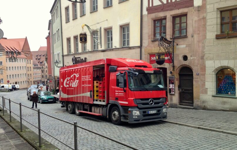 a red truck driving down a street next to tall buildings