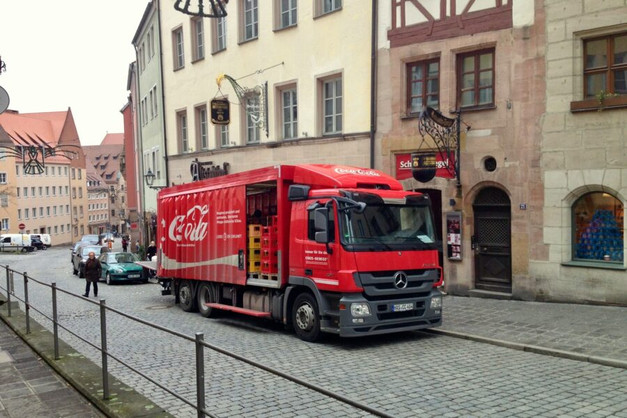 a red truck driving down a street next to tall buildings