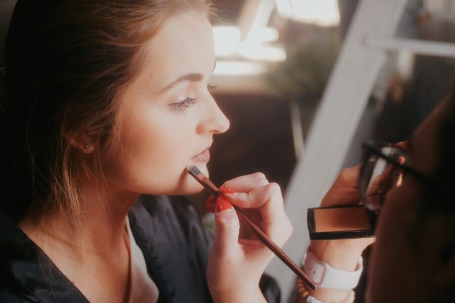 a woman is putting lipstick on her lips