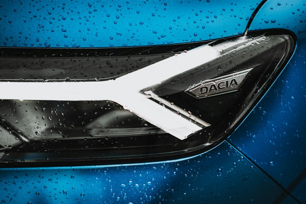 a close up of a blue car with rain drops on it