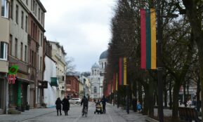 a group of people walking down a street next to tall buildings