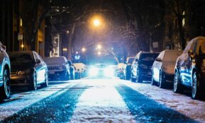 cars parked on both sides of the street during snowy nighttime