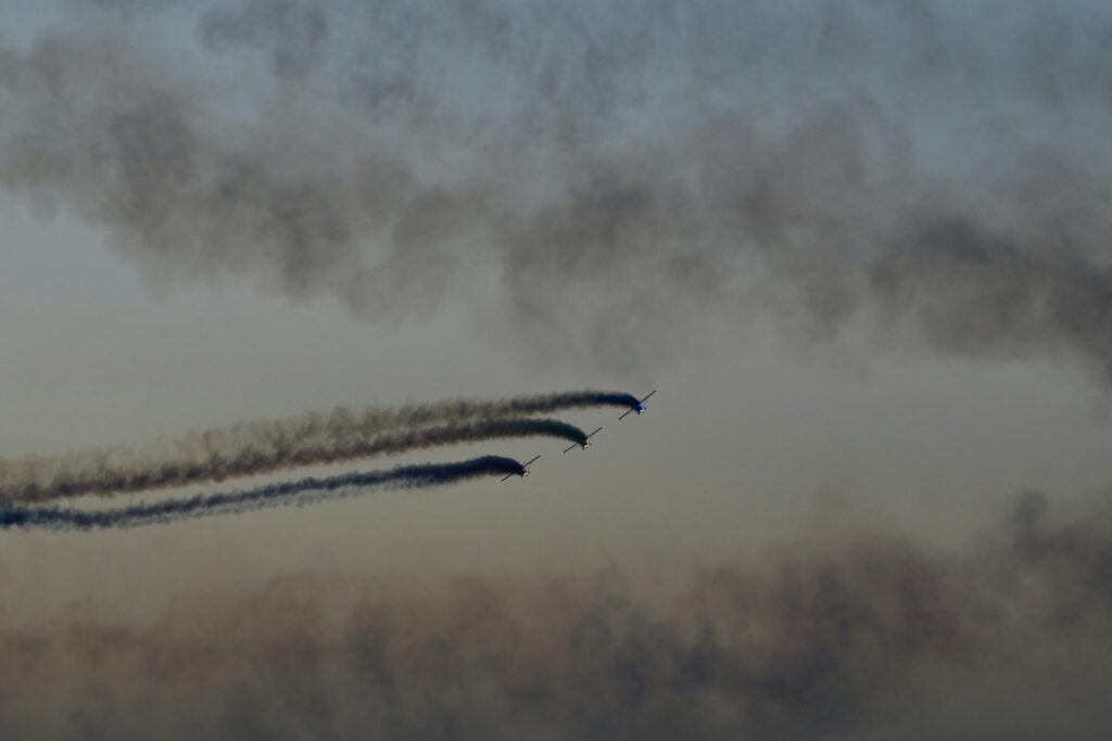 Three airplanes flying in formation with smoke trails.