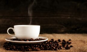 white ceramic mug and saucer with coffee beans on brown textile