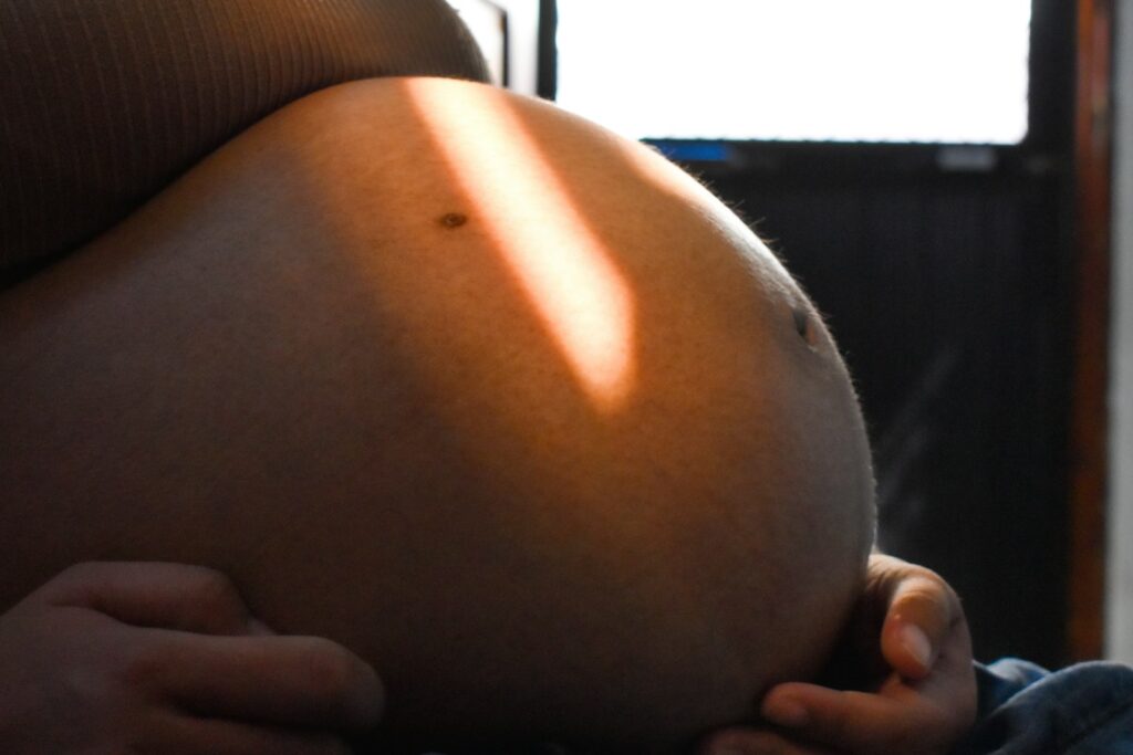 Pregnant woman's belly illuminated by sunlight.