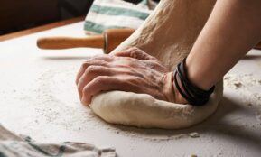 person making dough beside brown wooden rolling pin