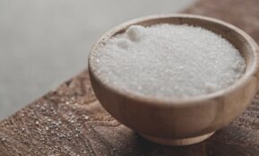 a wooden bowl filled with sugar on top of a wooden table