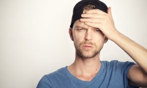 man in blue crew neck shirt covering his face