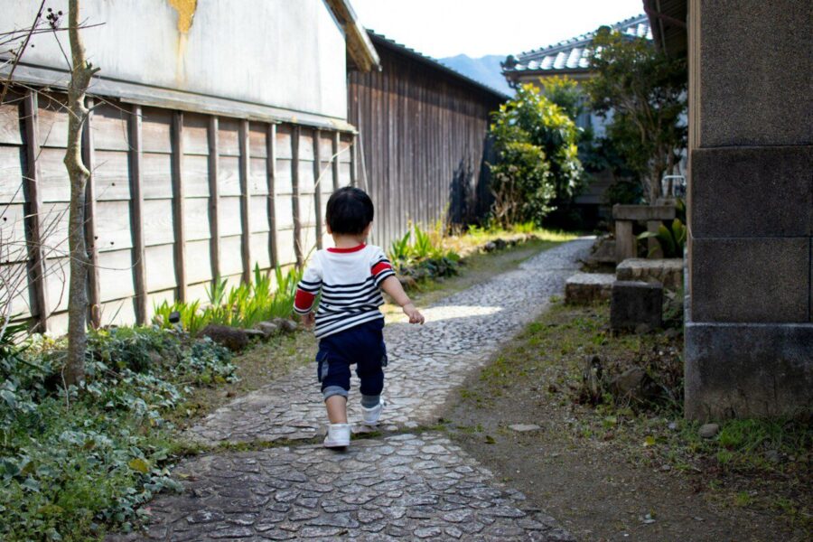 boy in black and white stripe t-shirt and black shorts standing on gray concrete pathway
