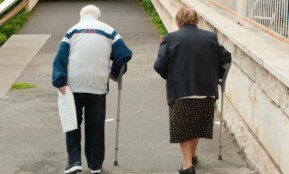 Elderly couple walking with crutches up stairs