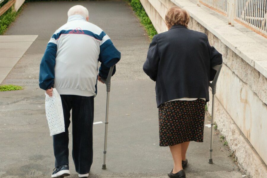 Elderly couple walking with crutches up stairs
