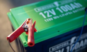 a red and green battery with a pair of pliers attached to it