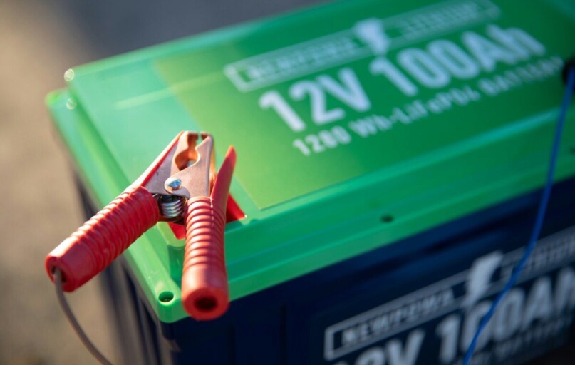 a red and green battery with a pair of pliers attached to it