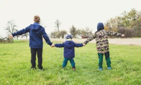 three children holding hands standing on grasses