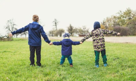 three children holding hands standing on grasses