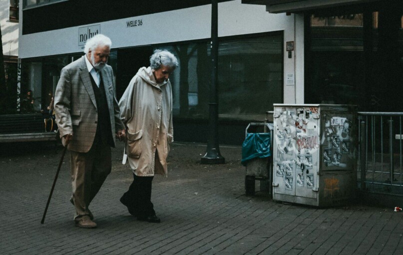 man in black suit standing beside woman in white coat