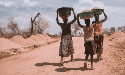 three women carrying basin while walking barefoot