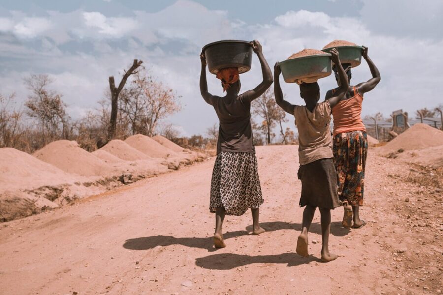 three women carrying basin while walking barefoot