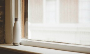 gray and white vacuum flask beside window frame