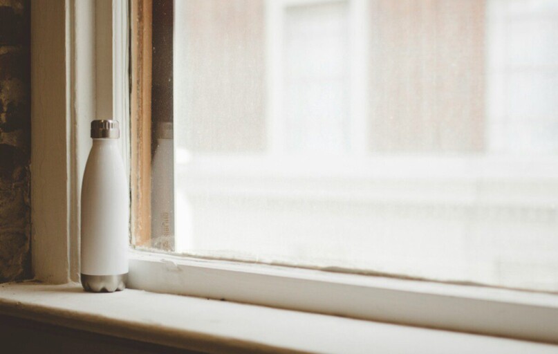 gray and white vacuum flask beside window frame