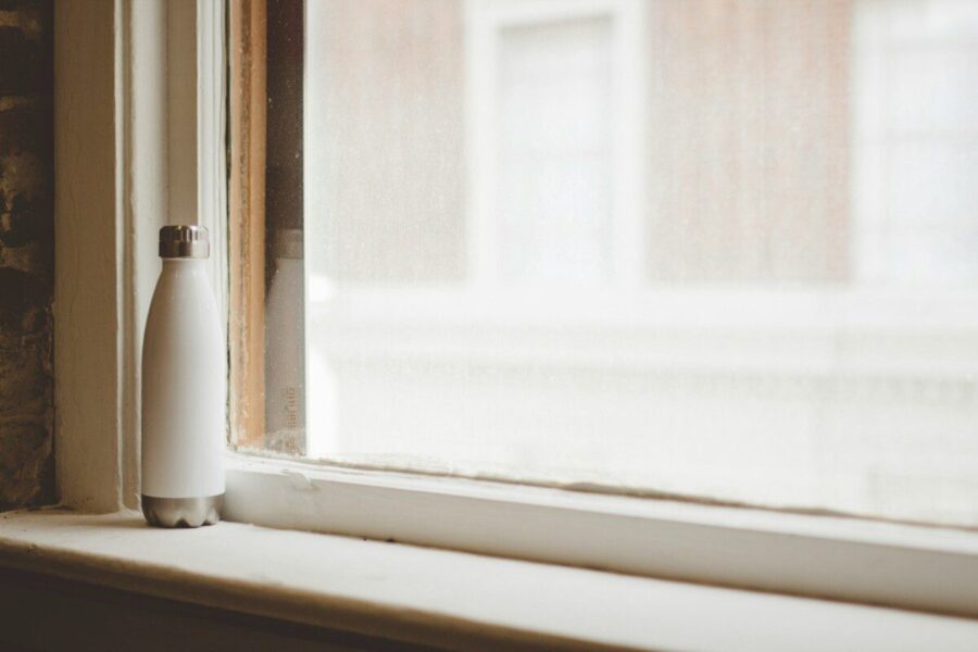 gray and white vacuum flask beside window frame