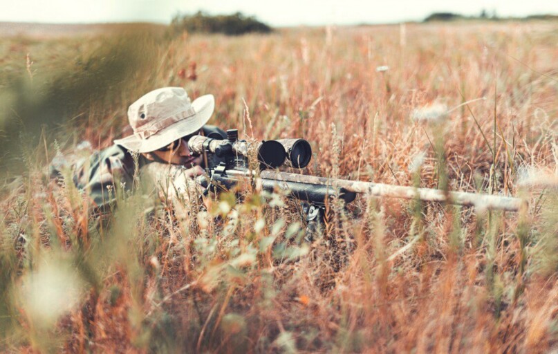 man in brown jacket and black pants sitting on brown grass field during daytime
