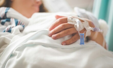 a woman laying in a hospital bed with an iv in her hand