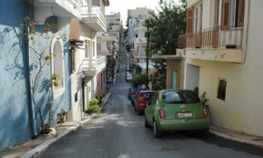 green car parked beside white concrete building during daytime
