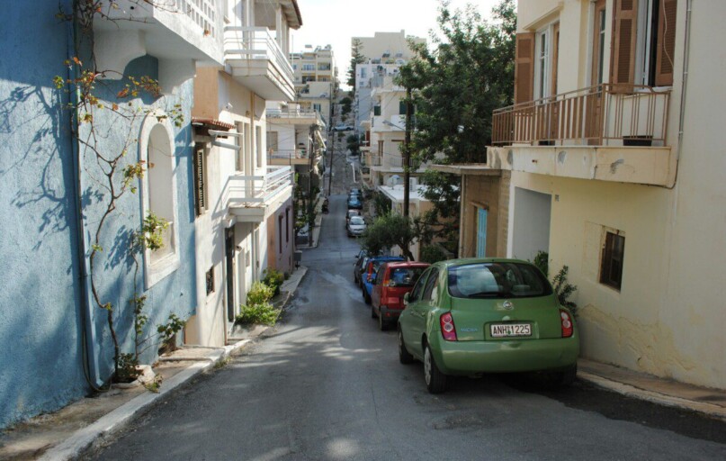green car parked beside white concrete building during daytime