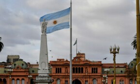 Argentinian flag waving near a prominent building.