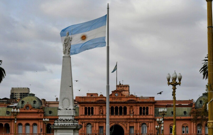 Argentinian flag waving near a prominent building.