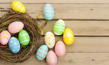 a bird's nest with painted eggs on a wooden surface