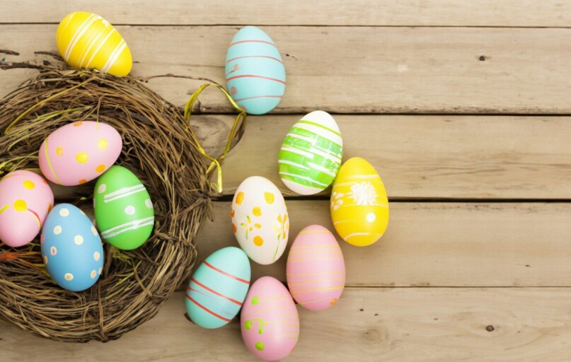 a bird's nest with painted eggs on a wooden surface