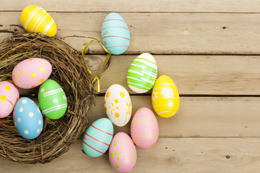 a bird's nest with painted eggs on a wooden surface