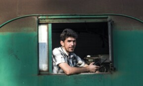 man in white and black plaid button up shirt sitting on green and black bus