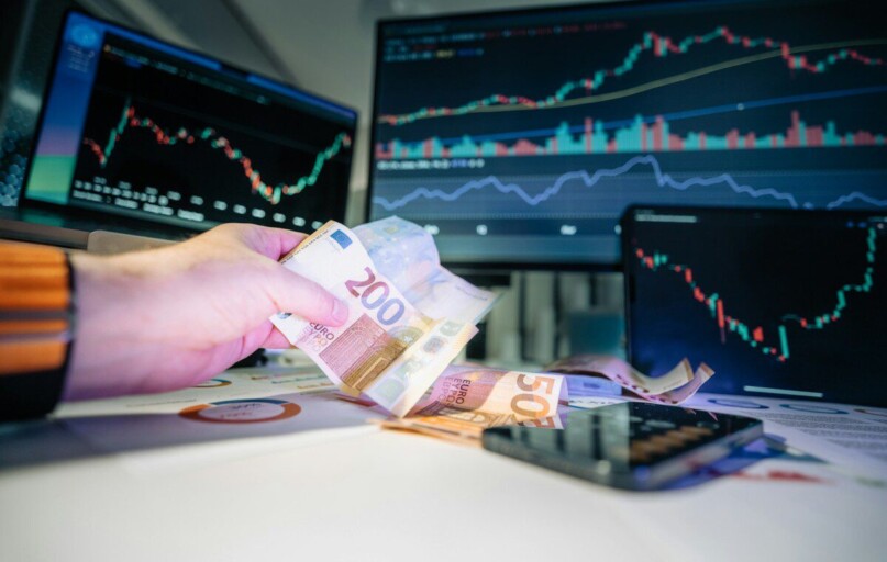 A person holding money in front of a computer screen