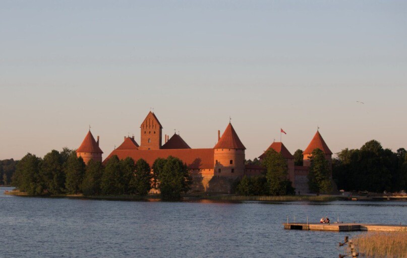 a castle sitting on top of a lake next to a forest