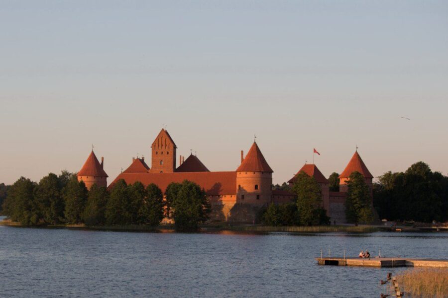 a castle sitting on top of a lake next to a forest