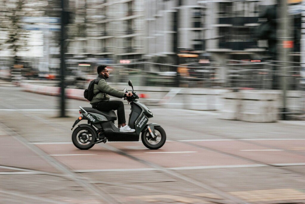 man in green jacket riding motorcycle on road during daytime