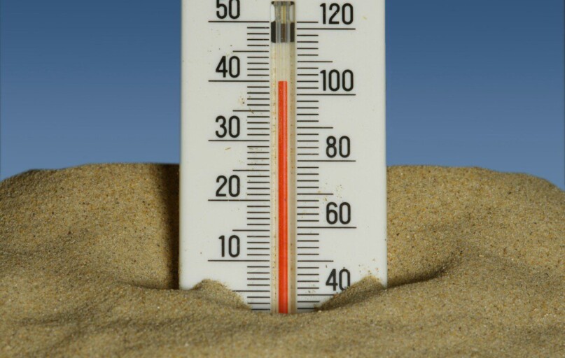 A thermometer in the sand with a blue sky in the background
