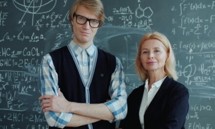 A young man and older woman in front of chalkboard.