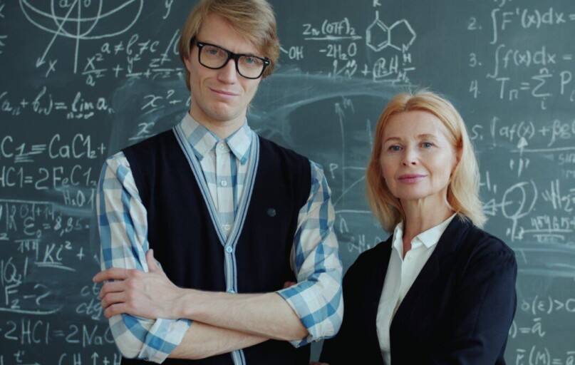 A young man and older woman in front of chalkboard.