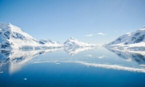 mountain with snow near body of water